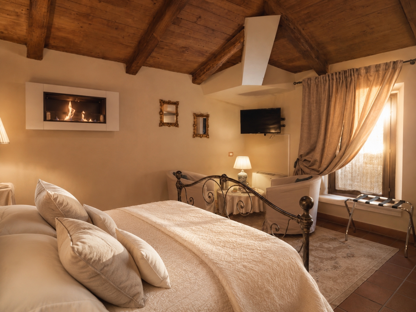 Junior Suite con camino a Villa Sant'Erasmo, letto in ferro battuto con baldacchino, travi a vista e poltrona a dondolo