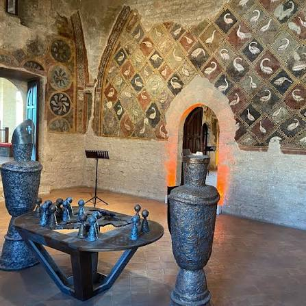 Sala interna del Palazzo di Bonifacio VIII ad Anagni con affreschi medievali a losanghe e medaglioni, arco acuto illuminato da luce calda e pavimento in cotto
