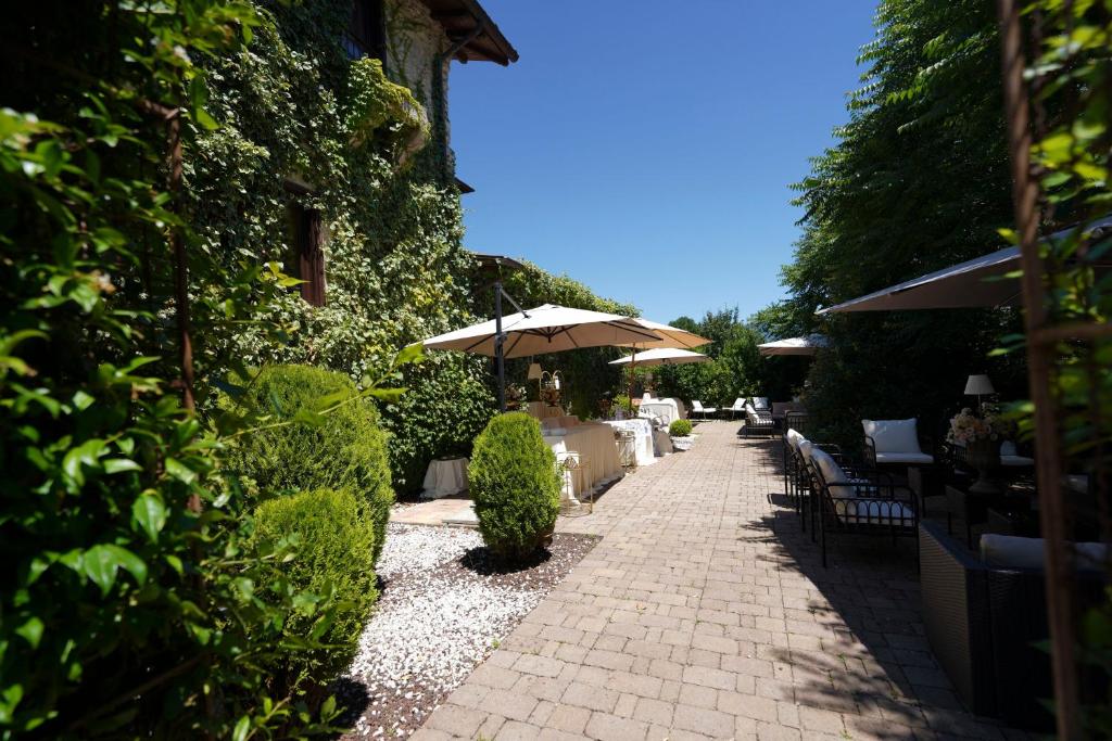Corte in pietra di Villa Sant'Erasmo tra siepi, ombrelloni e salotti all'aperto