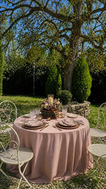 Tavola per due con mise en place rosa sotto un grande albero nel giardino