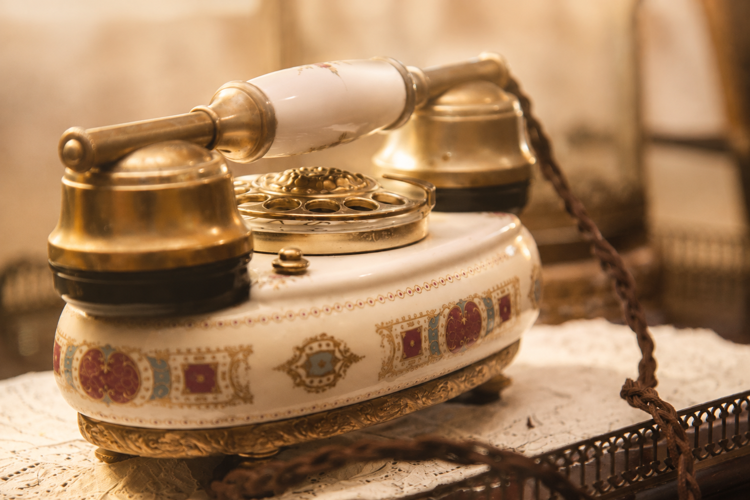 Telefono antico in porcellana e ottone su un tavolo ricamato