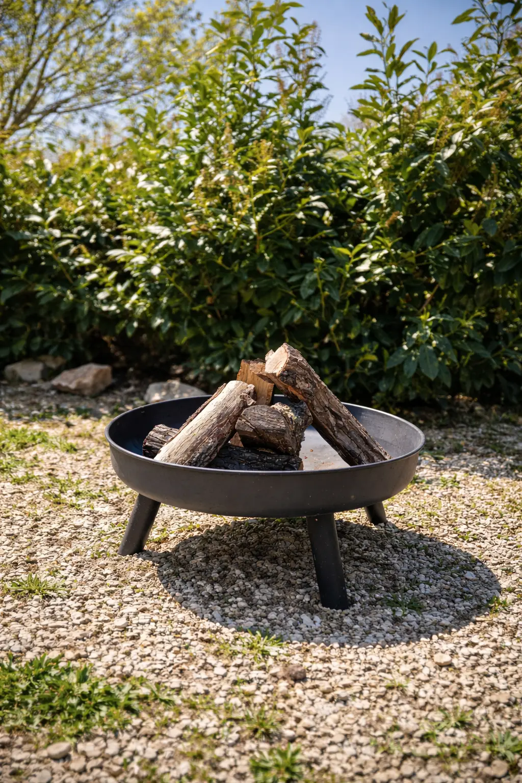 Braciere nel giardino tra ghiaia e siepi sempreverdi