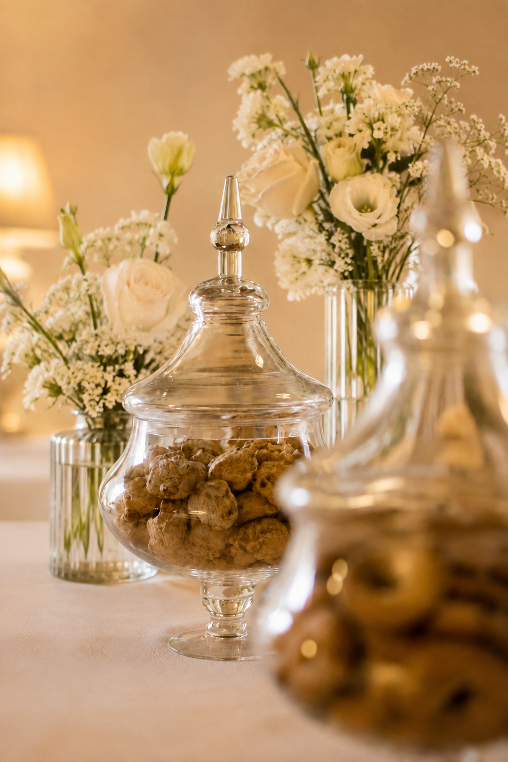 Biscotti fatti in casa nelle alzate di vetro tra composizioni di fiori bianchi a Villa Sant'Erasmo