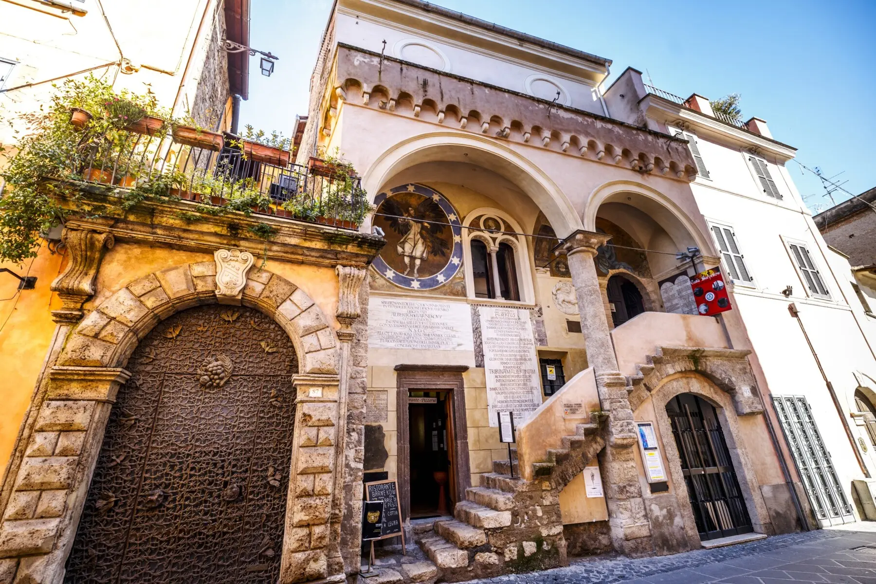 La facciata di Casa Barnekow ad Anagni con la loggia a due archi, gli affreschi con angeli su fondo stellato, le iscrizioni latine e la scalinata in pietra