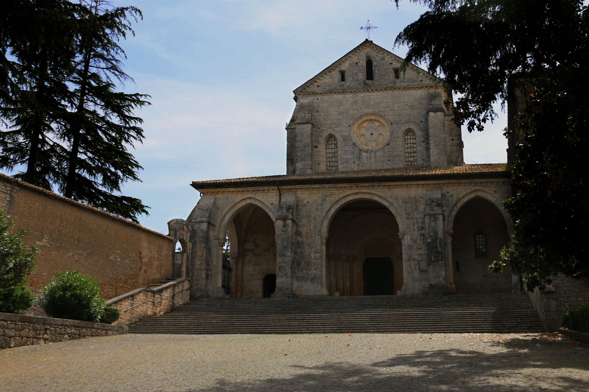 La facciata gotico-cistercense dell'Abbazia di Casamari vista di scorcio, con il sentiero in pietra che conduce al portale