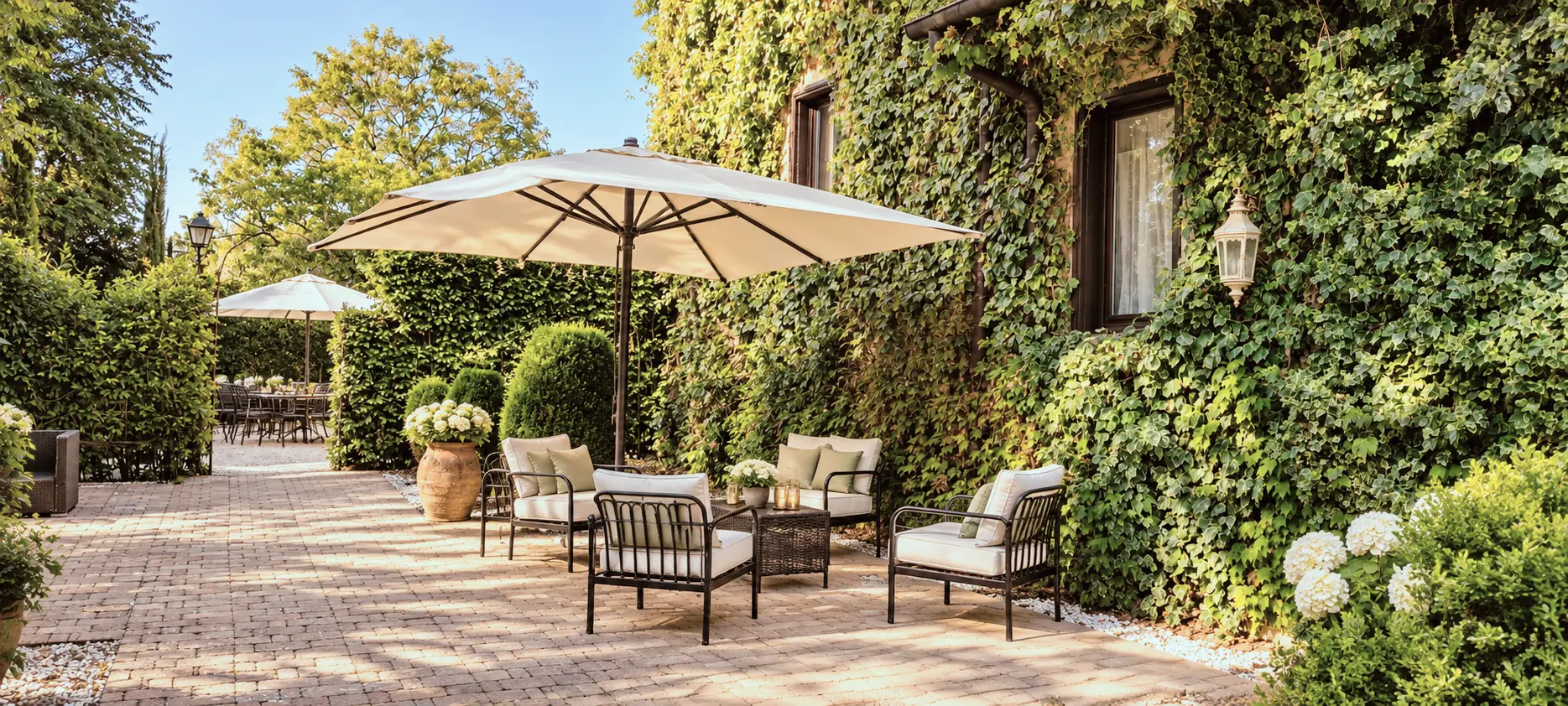 Lounge all'aperto nel giardino di Villa Sant'Erasmo, ombrellone, salotti e facciata ricoperta di edera